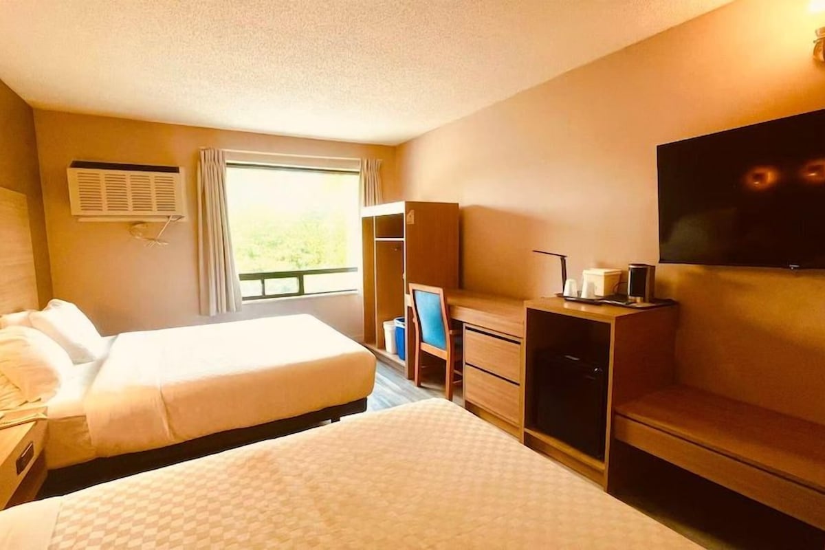 Een hotelkamer met een bed, een bureau met stoel, een televisie en een kledingkast.