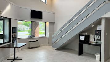 A modern interior with a staircase, a reception desk, and a window overlooking a street.