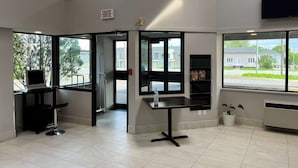 Un interior moderno con un mostrador de recepción, una computadora, una planta en maceta y un televisor.