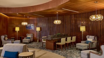 A lobby with a curved wooden ceiling, a reception desk, and several seating areas with lamps and chairs.
