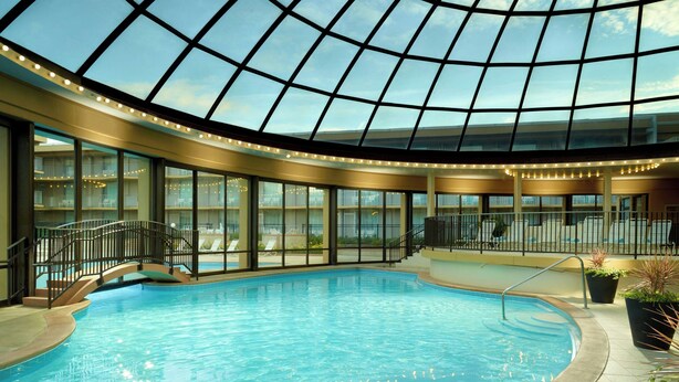 Une piscine intérieure dotée d’un toit en verre, entourée de balcons et de rampes.