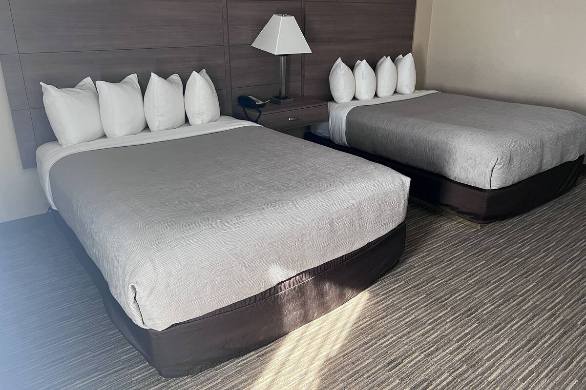 Ein Hotelzimmer mit zwei Betten, einem Nachttisch, einer Lampe und einem Telefon.