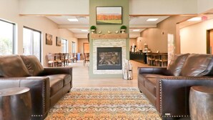 Eine Lobby mit Ledersofas, einem gemusterten Teppich, einem Kamin und einem Essbereich im Hintergrund.