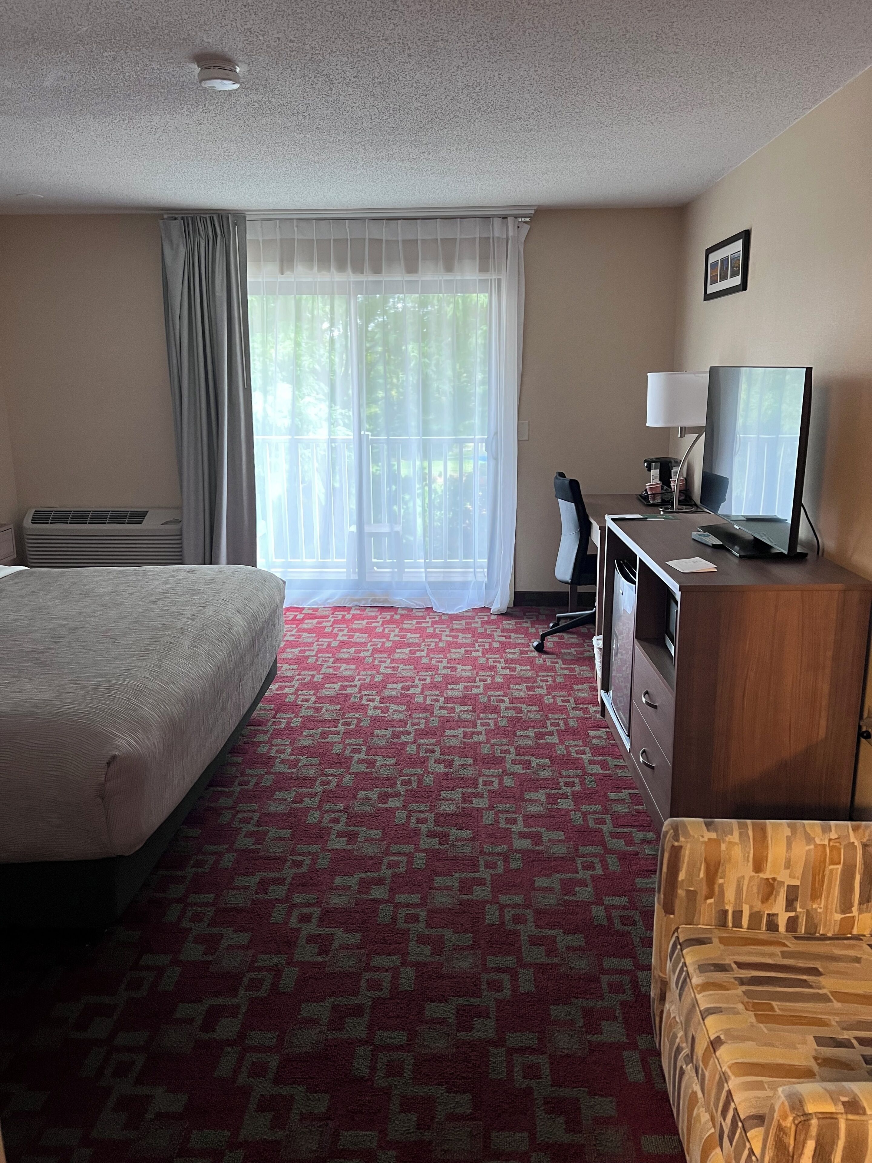 Una camera d'albergo con un letto, una scrivania con un computer, una televisione e una sedia.