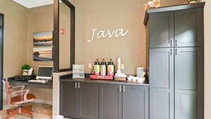 Ein Empfangsbereich mit einem Schreibtisch, einem Computer und einem an der Wand befestigten Schild mit der Aufschrift 'Java'.