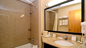 A bathroom with a bathtub, a sink, and a large mirror.