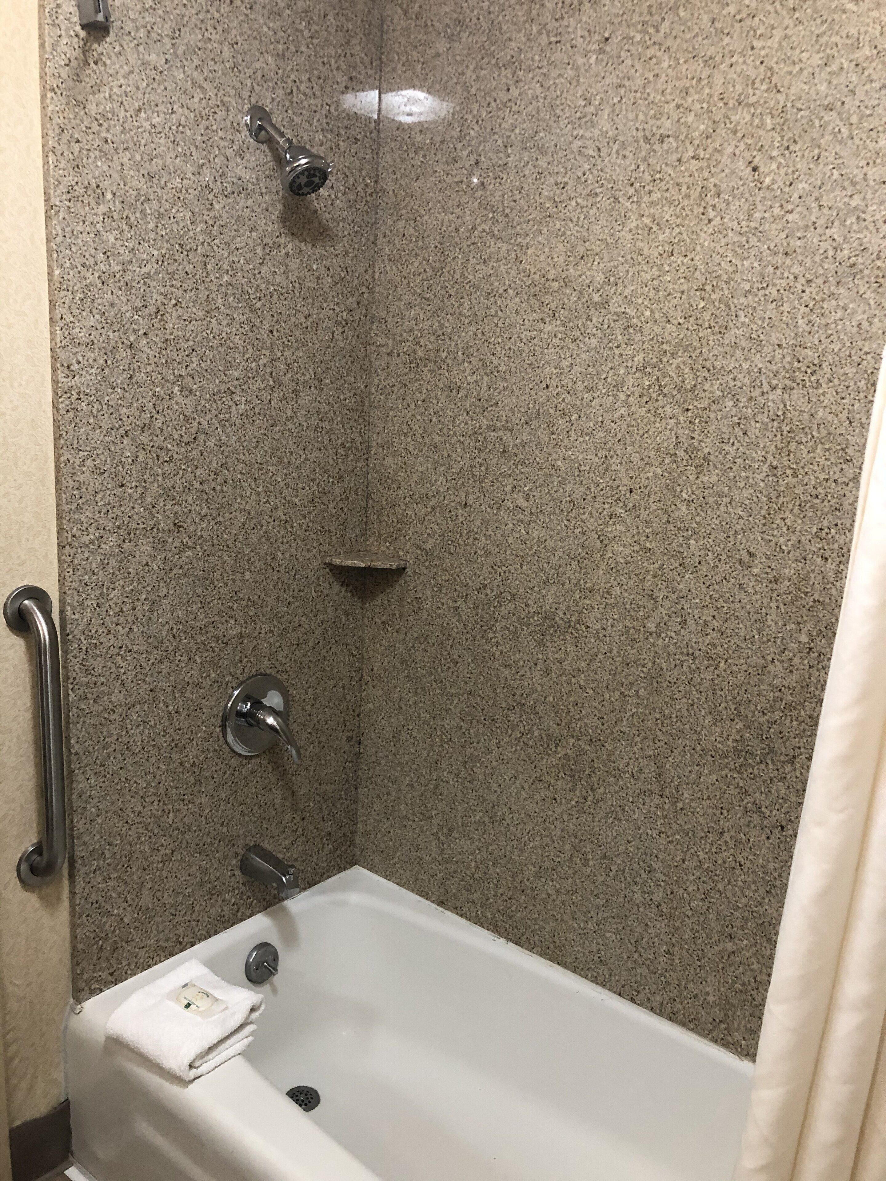 Un baño con bañera, ducha y barra de apoyo.