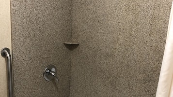 Un baño con bañera, ducha y barra de apoyo.