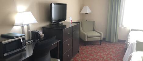 Une chambre d’hôtel équipée d’un bureau, d’une télévision, d’une chaise, d’une lampe et d’un lit.