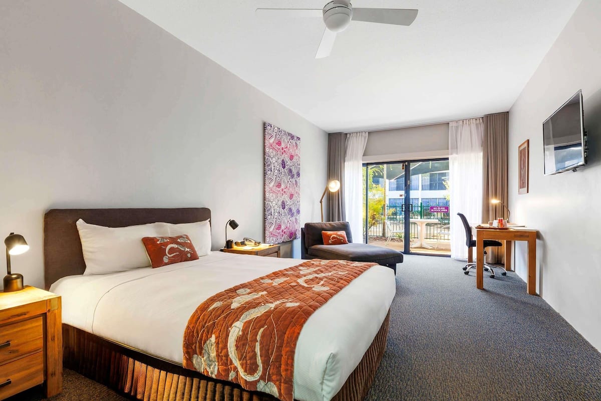 Ein Hotelzimmer mit Bett, Schreibtisch, Stuhl und Blick nach draußen.