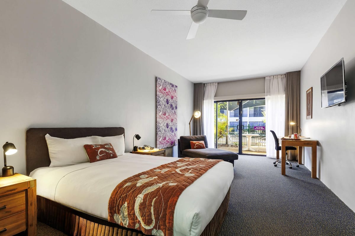 Ein Hotelzimmer mit Bett, Schreibtisch, Stuhl, Fernseher und einem Balkon mit Blick.