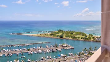 A marina with numerous boats docked, a clear blue sky, and a view of the ocean.