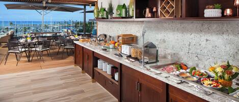 Area buffet con diversi tipi di cibo e vista sull'oceano.