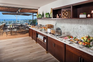 A buffet area with a variety of food items and a view of the ocean.