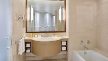 A modern bathroom with a large mirror, a sink with a wooden vanity, a bathtub, and a shower area.