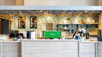A coffee shop counter with a menu board, espresso machine, and a green coffee grinder.