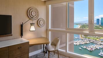 Een moderne hotelkamer met een groot raam met uitzicht op een jachthaven en stadsbeeld.