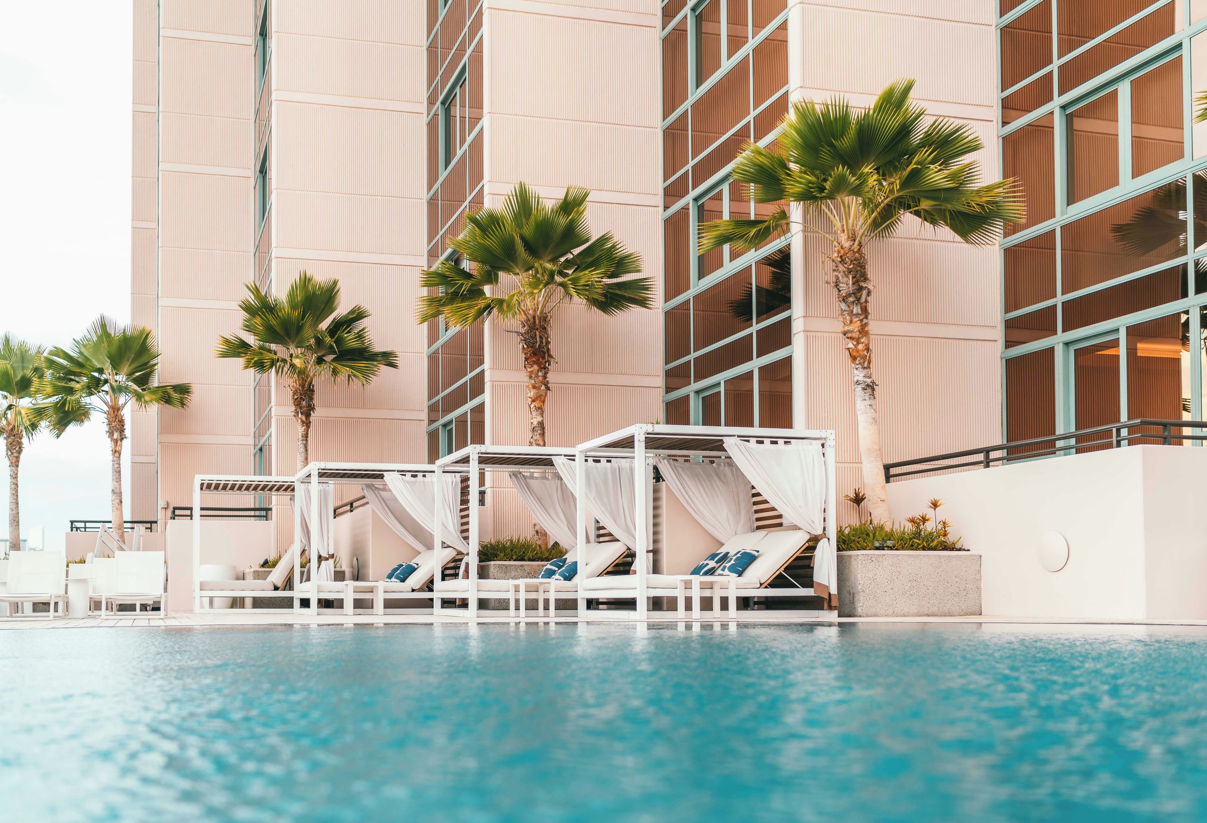 A pool area with lounge chairs and a canopy structure, surrounded by tall buildings.
