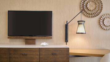 Una sala de estar moderna con un televisor de pantalla plana montado en una pared de madera, una mesa de centro de vidrio y un mueble de madera con cajones.
