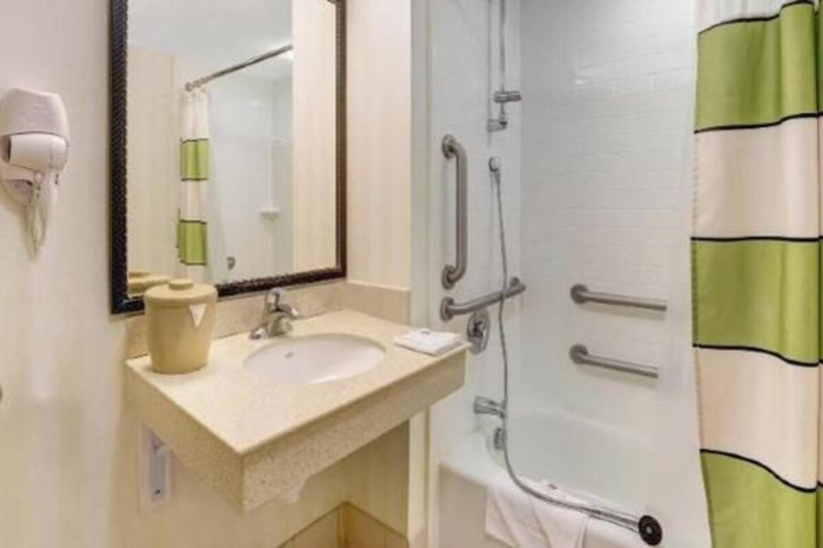 A bathroom with a sink, mirror, and shower.