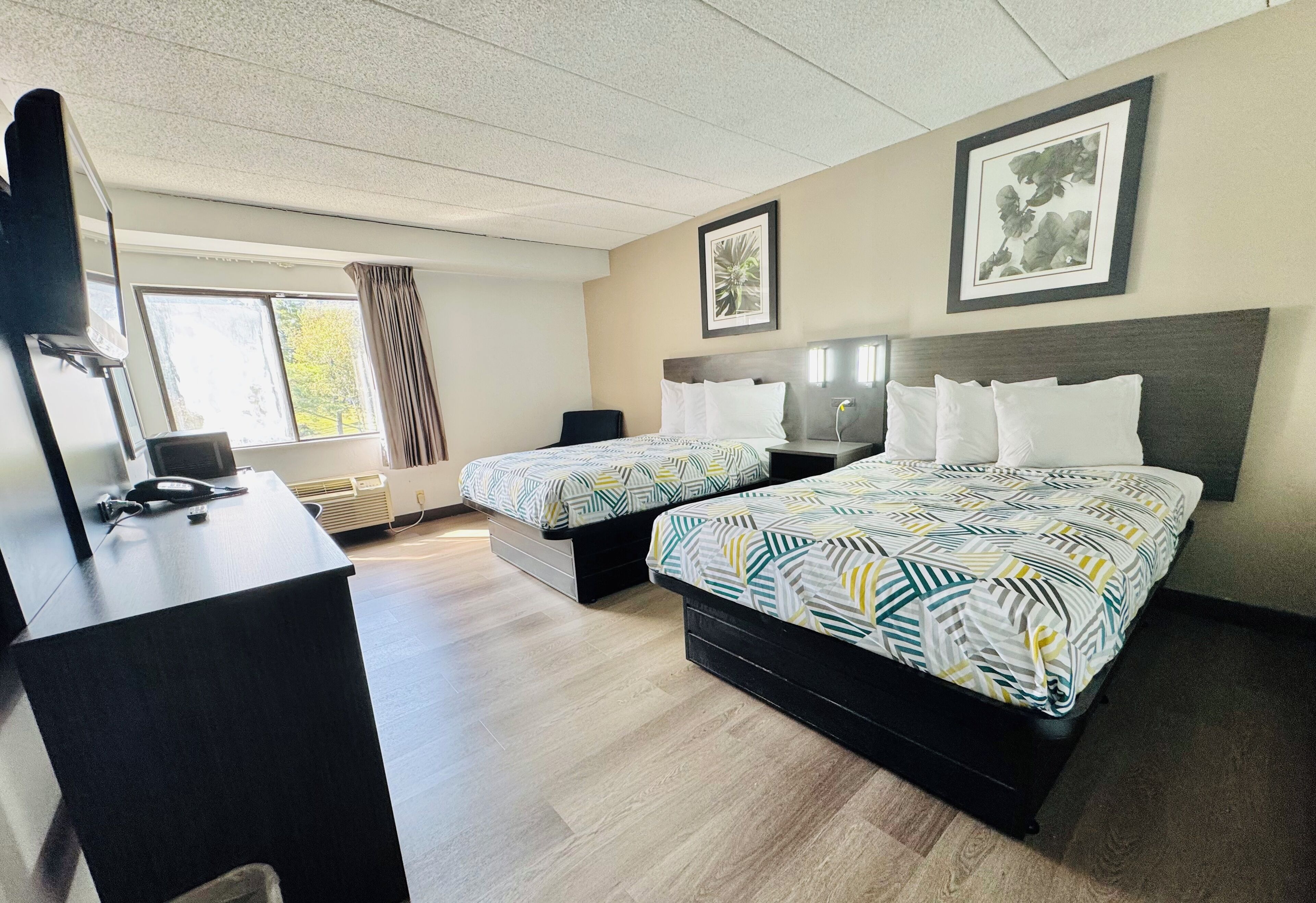 Une chambre d’hôtel avec deux lits, un bureau et une grande fenêtre.
