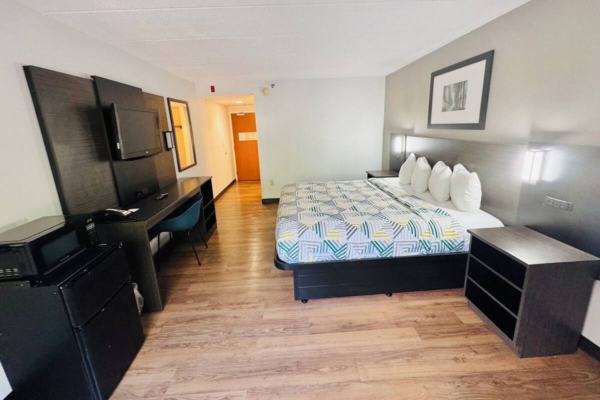 Ein Hotelzimmer mit Bett, Schreibtisch, Fernseher und Kleiderschrank.