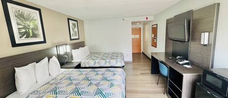 A hotel room with two beds, a desk, a television, and a microwave.