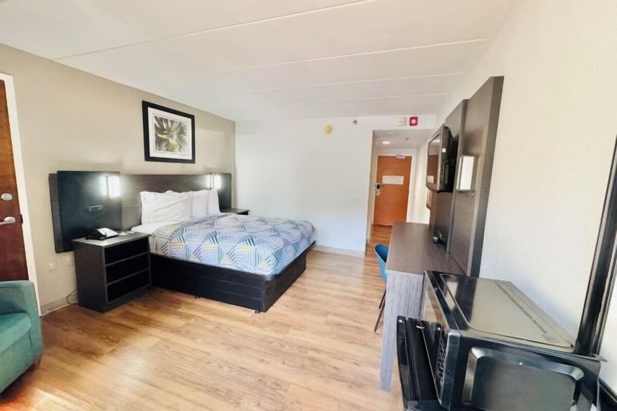A hotel room with a bed, bedside table, and a television.
