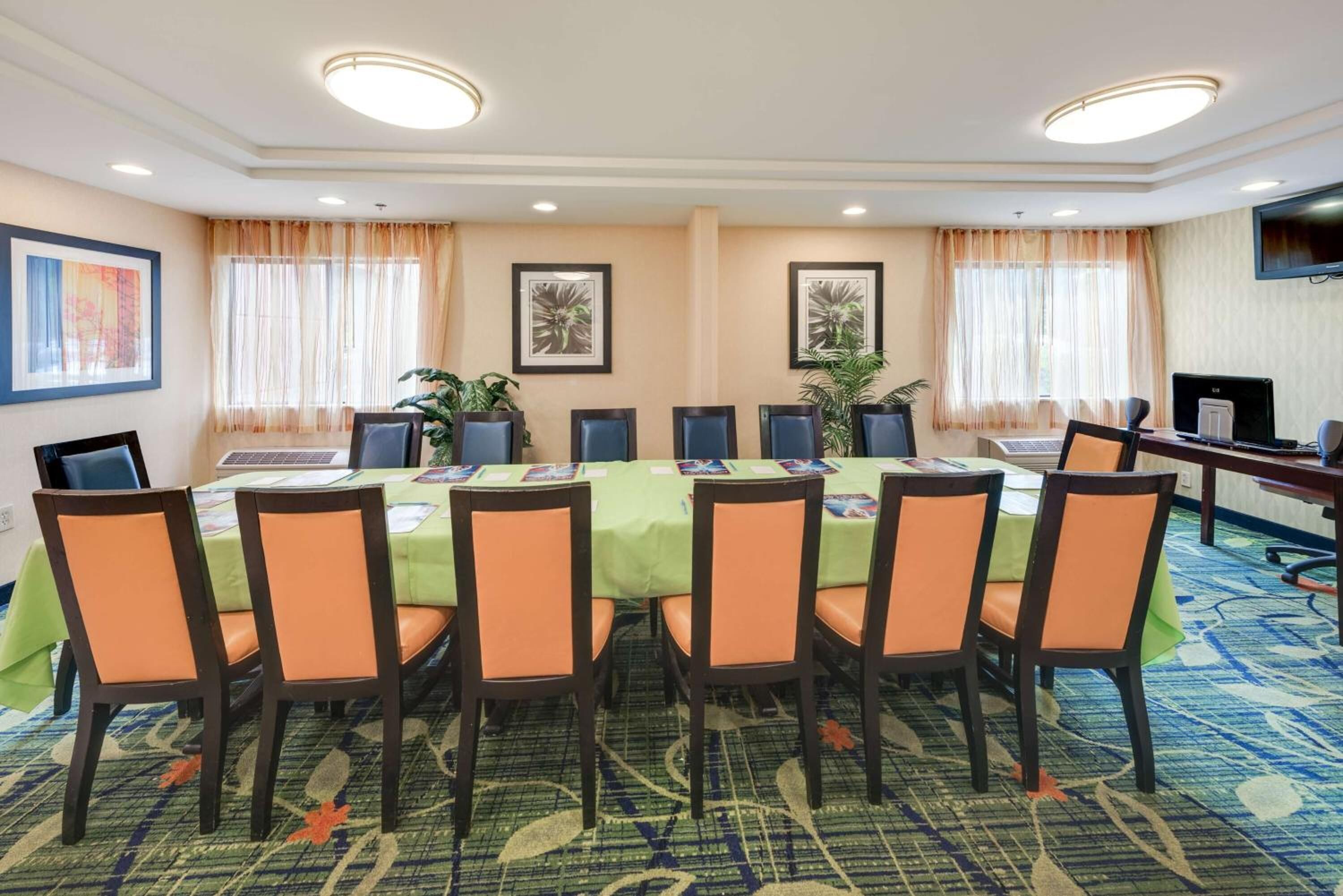 A conference room with a long table, chairs, laptops, and framed artwork on the walls.