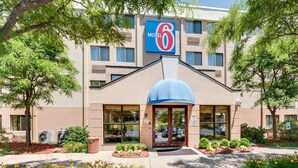 A Motel 6 building with a large sign, a blue awning, and a landscaped entrance area.