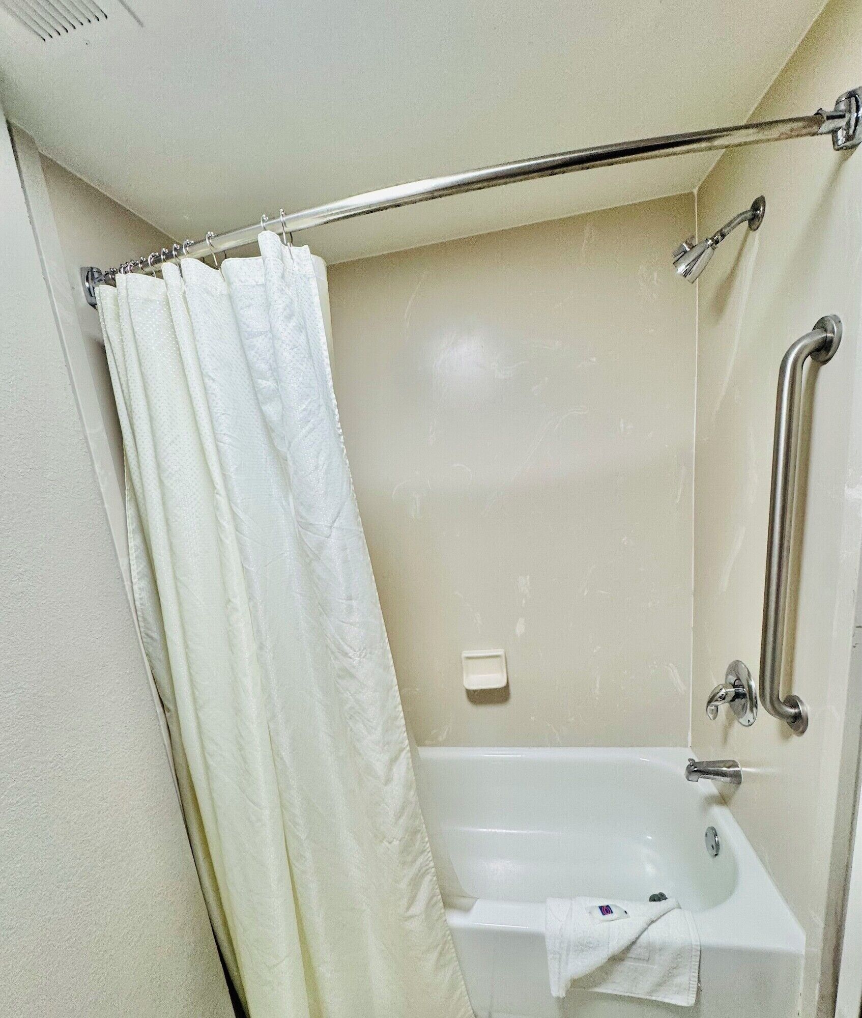 A bathroom with a bathtub, a shower area, and a grab bar.