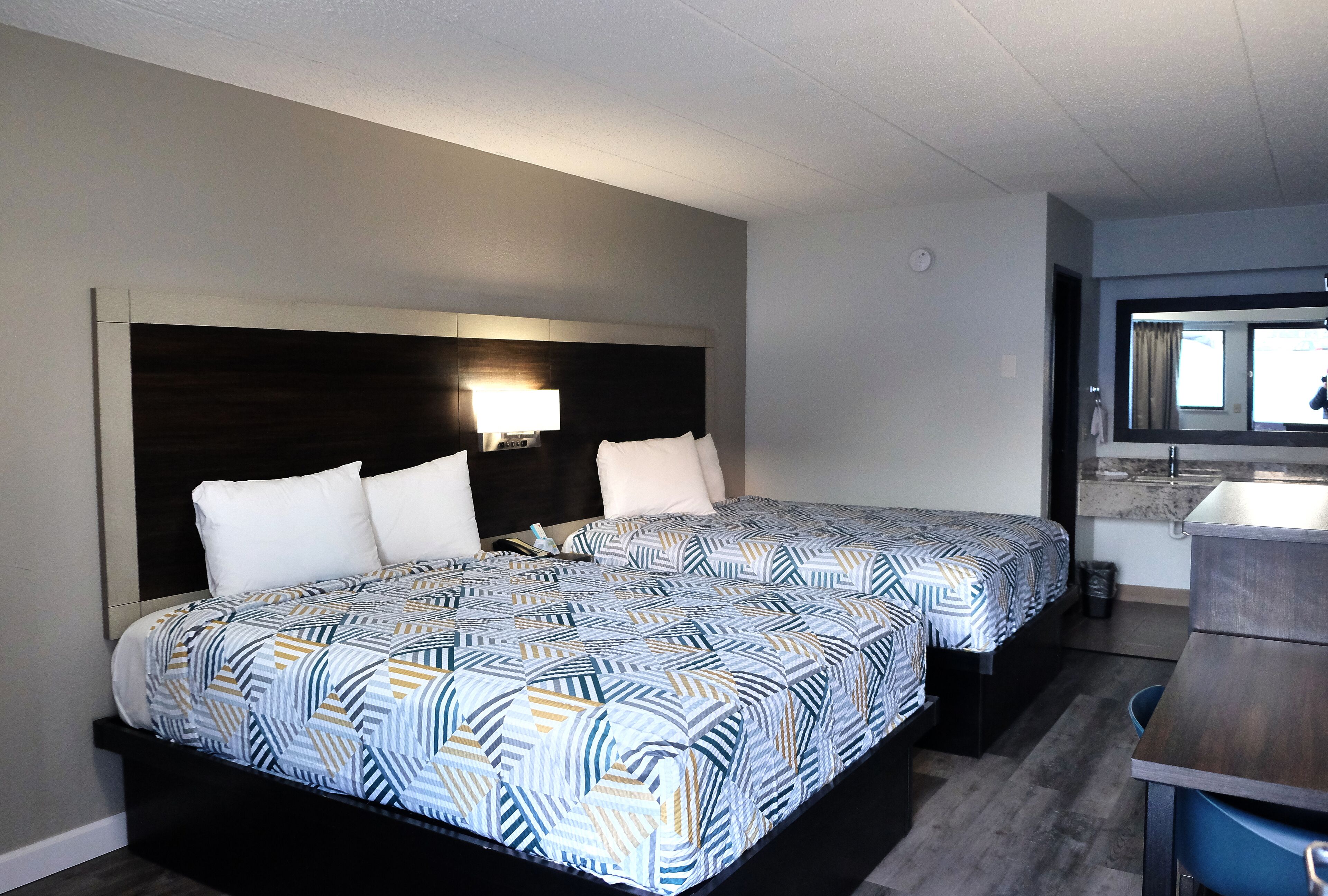 Una habitació d'hotel amb dos llits, una taula de treball i un bany.