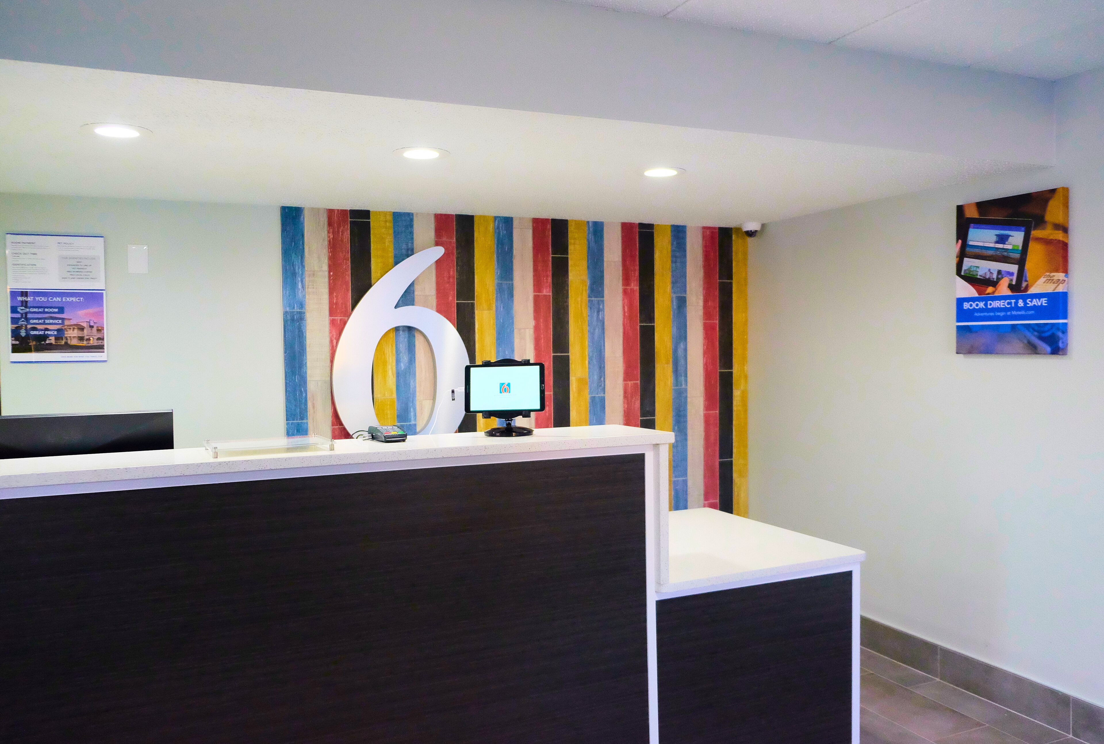A reception desk with a large number '6' sign, a computer monitor, and a colorful striped wall.