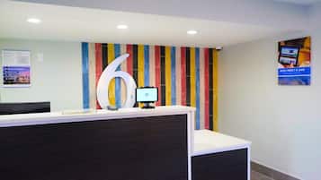 A reception desk with a large number '6' sign, a computer monitor, and a colorful striped wall.