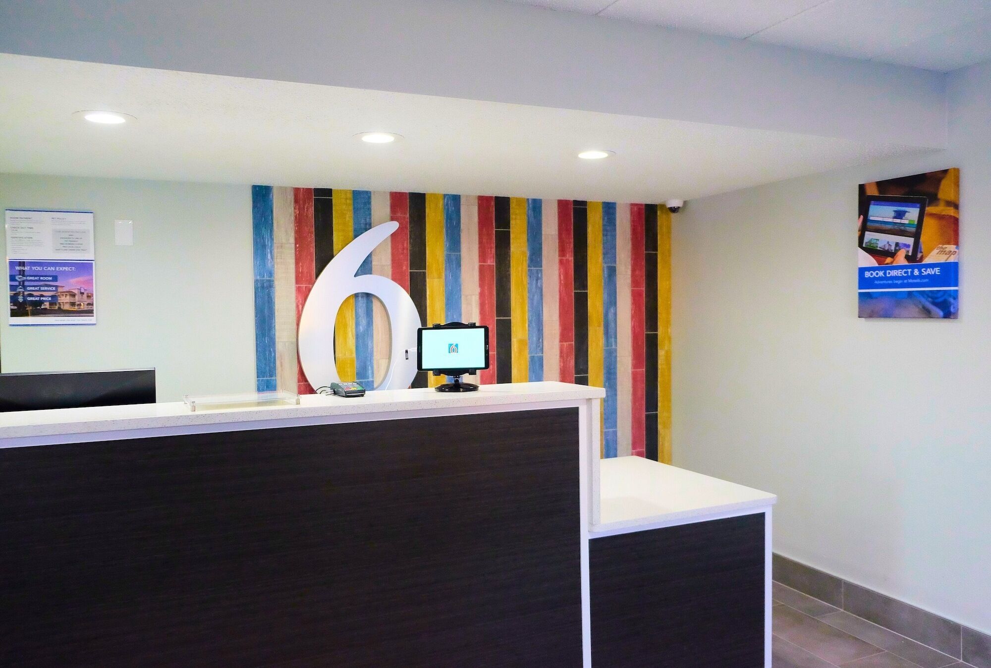 A reception desk with a large number '6' sign, a computer monitor, and a colorful striped wall.
