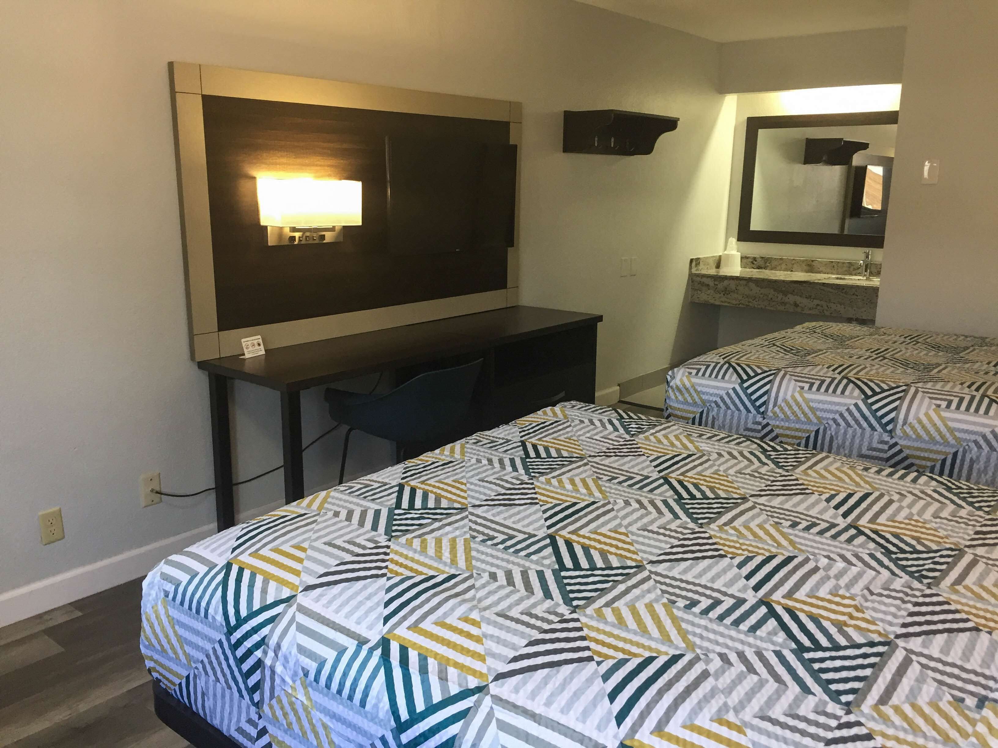 Une chambre d’hôtel avec un lit, un bureau et un miroir.