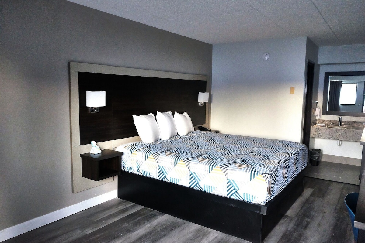 A modern hotel room with a large bed, bedside tables, and a built-in desk.
