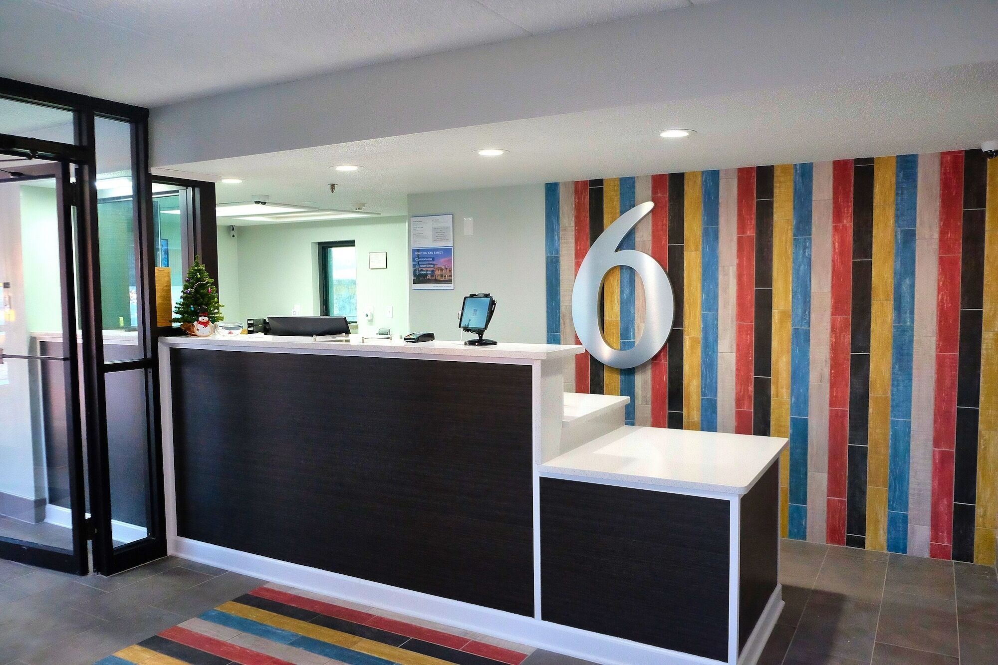 A reception area with a modern design, featuring a large number '6' on the wall, a reception desk, and a colorful striped wall.