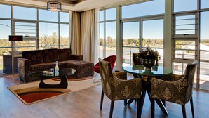 Un salón amplio con un gran ventanal, un sofá, una mesa de centro y una zona de comedor con sillas.
