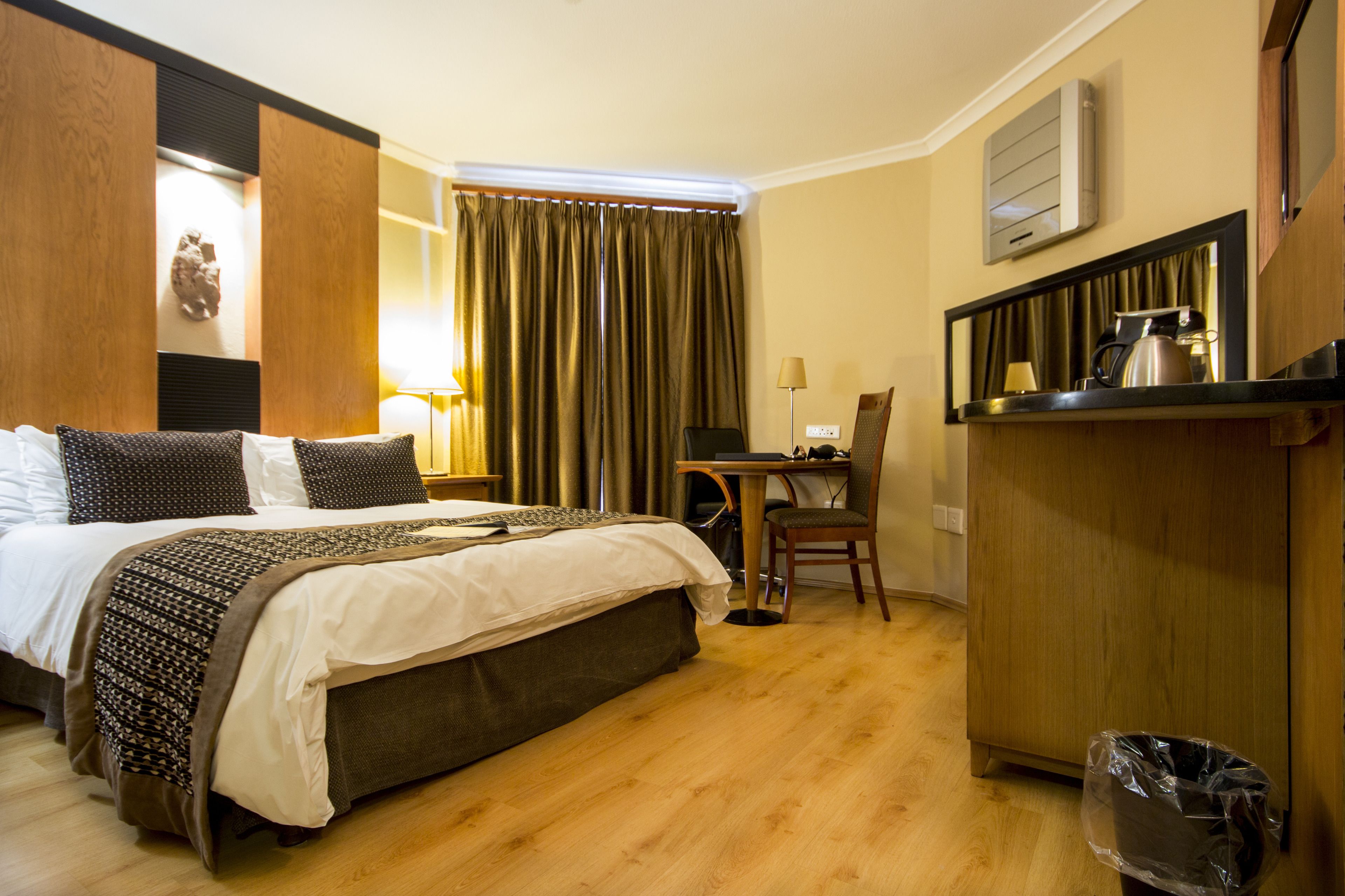 A hotel room with a bed, desk, chair, and a small kitchenette area.