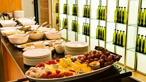 Un bufé con diversos alimentos y una exhibición de botellas de vino verde.