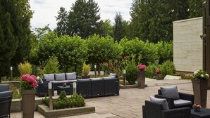 An outdoor patio area with wicker furniture, potted plants, and a stone floor. - Sunday Hotel Bad Soden (Bad Soden am Taunus)