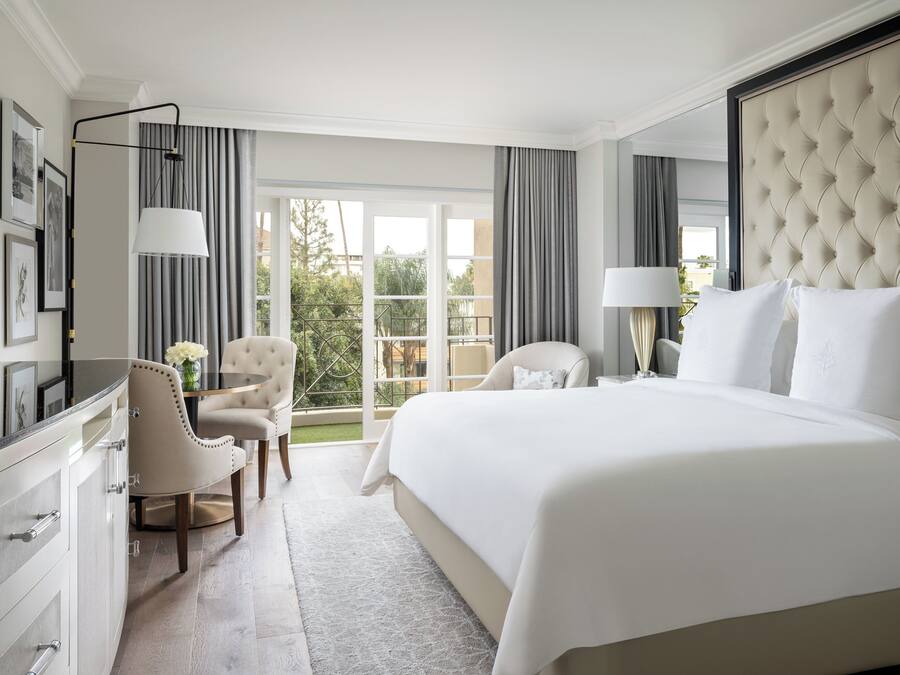 Quarto de hotel com uma cama grande, uma escrivaninha, uma cadeira e vista para o exterior.
