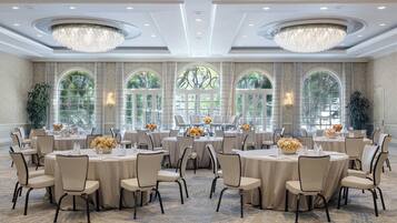 Un salón de banquetes con mesas redondas, sillas color beige y candelabros.