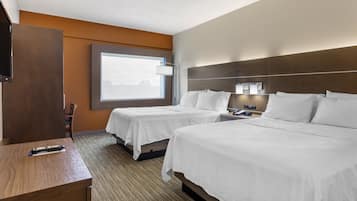 A hotel room with two beds, a desk, a TV, and a window with a view.