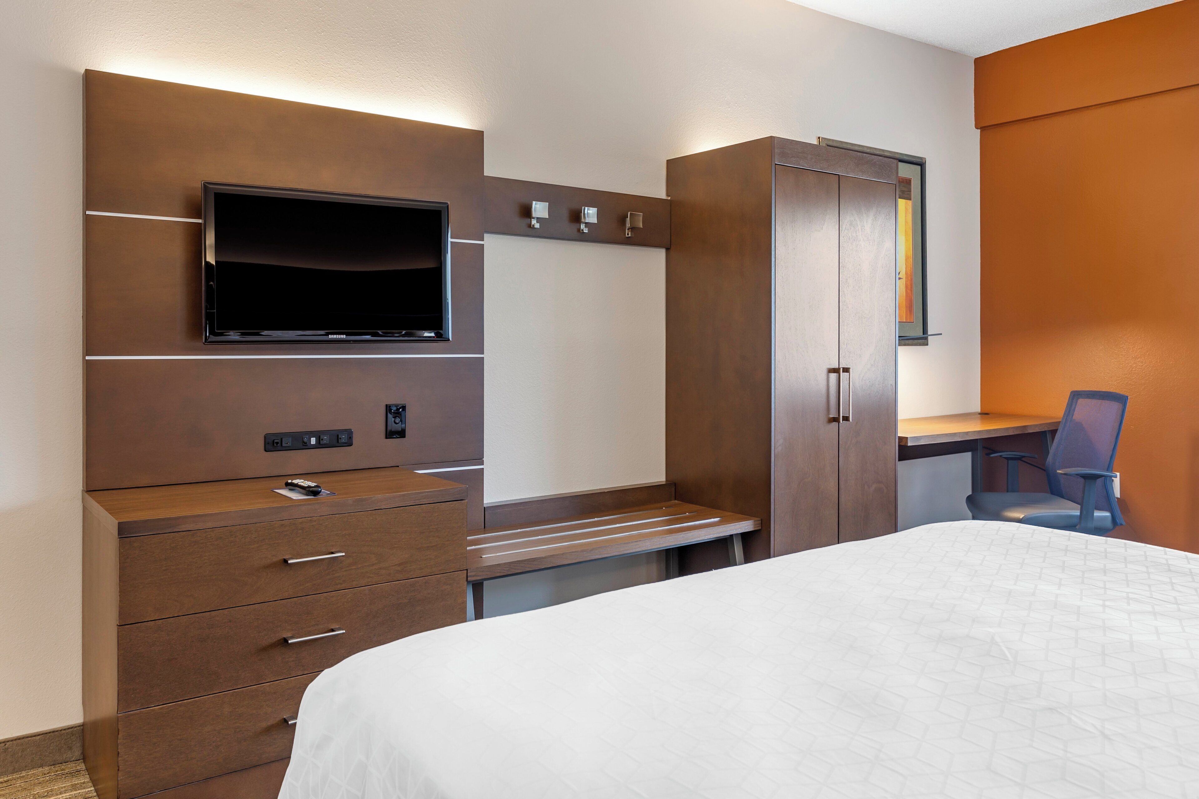 Une chambre d’hôtel équipée d’un lit, d’un bureau, d’une télévision et d’une armoire.