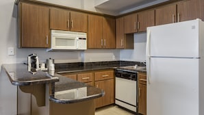 A kitchen with wooden cabinets, a microwave, a refrigerator, a dishwasher, and granite countertops. - Holiday Inn Express Branson-Green Mountain Drive by IHG (Branson)