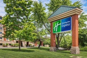 A Holiday Inn Express sign with a green and blue logo, set against a backdrop of trees and a building. - Holiday Inn Express Branson-Green Mountain Drive by IHG (Branson)