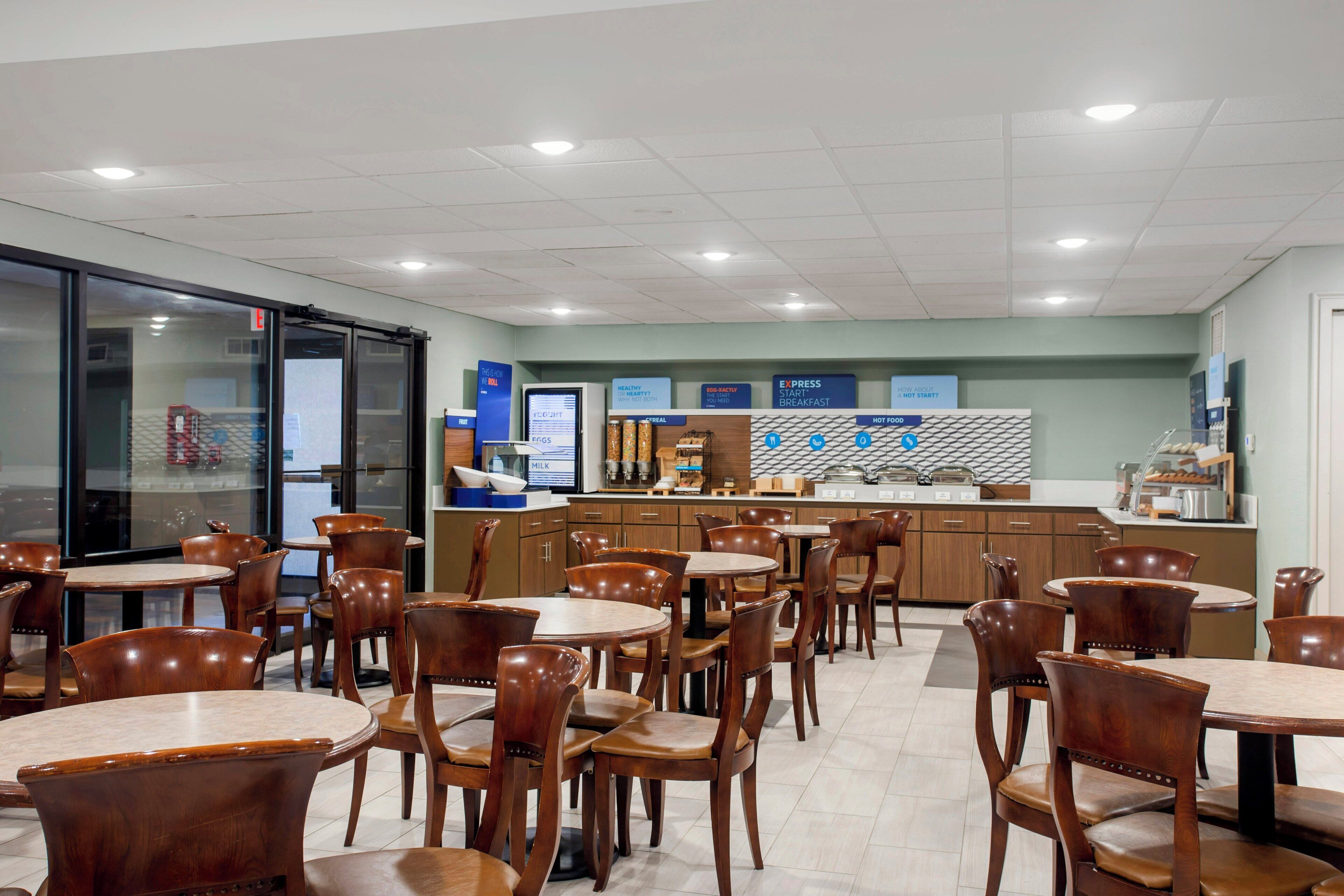 Un restaurant avec plusieurs tables et chaises, un comptoir où sont présentés les plats, et un menu affiché.