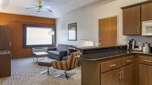 A modern hotel room with a kitchenette, a sofa, a patterned armchair, and a ceiling fan. - Holiday Inn Express Branson-Green Mountain Drive by IHG (Branson)